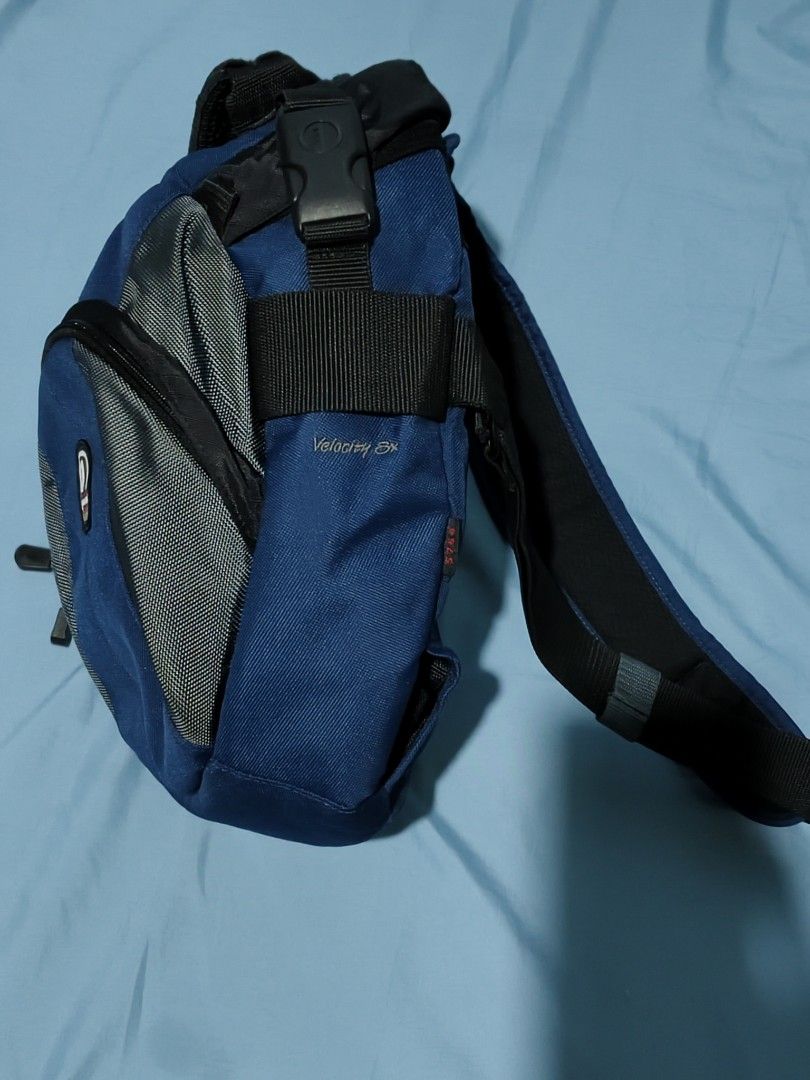Tamrac Camera Bag (Velocity 8x) (Category: Cross-body Bags) located in Muntinlupa City. Submitted by sariromrom (Listing ID 1429491170, Image 3). Description: Tamrac camera bag is designed to protect your camera gear. It features a blue and gray color scheme with multiple compartments and adjustable dividers. The bag has a top handle, a shoulder strap, and a buckle closure. It also has a side pocket for accessories. The interior has padded divide
