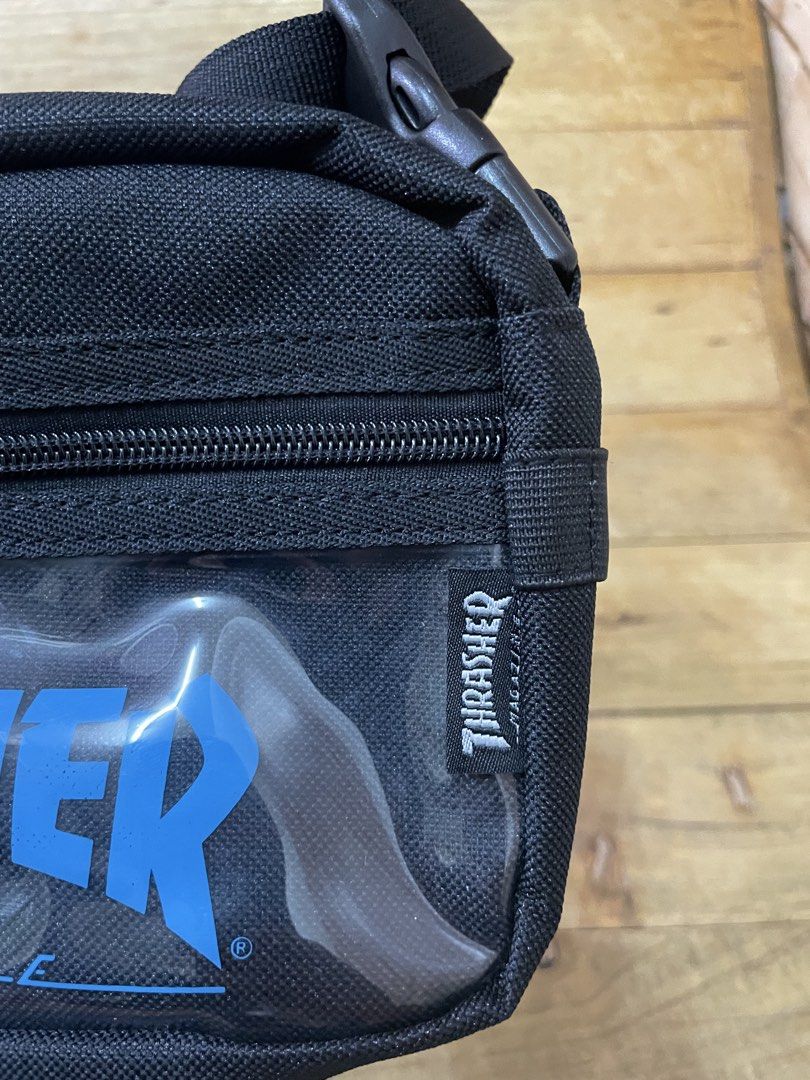 Thrasher Magazine Crossbody Bag (Category: Sling Bags) located in Manila. Submitted by vensen1798495 (Listing ID 1429485633, Image 2). Description: Black Thrasher crossbody bag. Features a clear front panel with the Thrasher logo in blue. Includes an adjustable strap and a zippered main compartment. The bag has a small Thrasher tag on the side and a tag with the brand's logo. Made in China. Brandnew no issues Dimes: 6Lx9W inches 650 pesos We ship