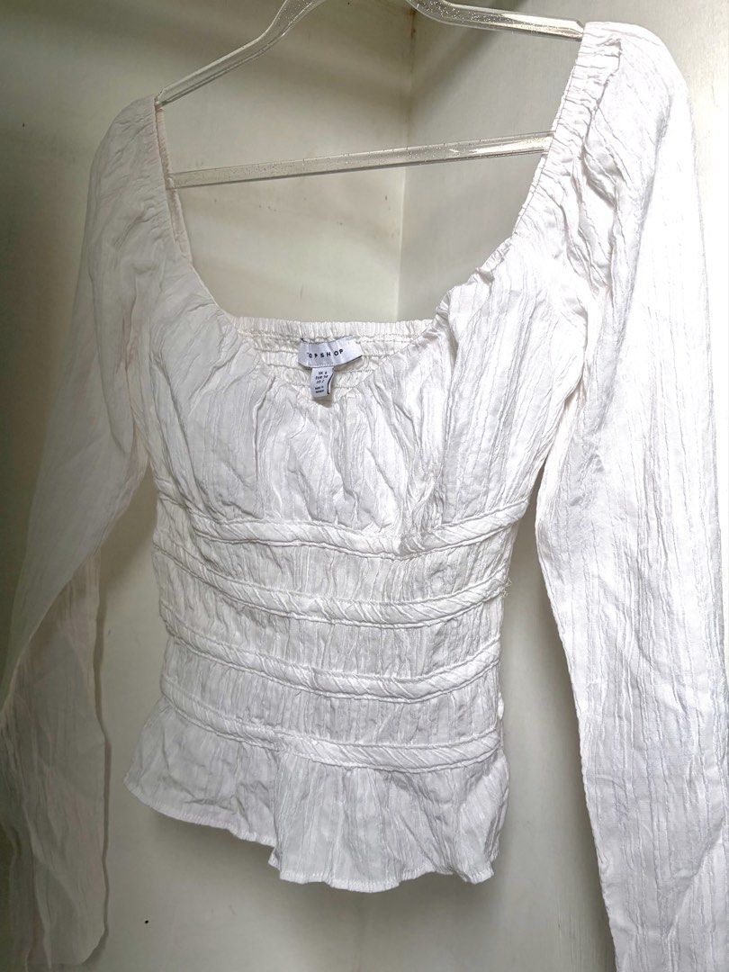 Topshop White Long Sleeve Top (Category: Blouses) located in Pulilan. Submitted by margaretsedit (Listing ID 1429416224, Image 1). Description: White long sleeve top from Topshop. Features a square neckline and shirred detailing on the bodice. The sleeves are long and the fabric has a textured appearance. The tag indicates a size UK 8. Perfect for a casual yet stylish look. Add 62 for SF.