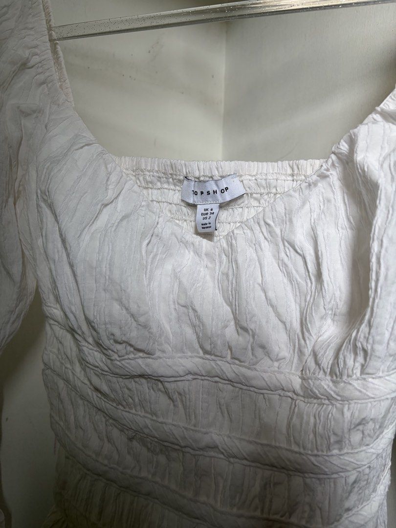 Topshop White Long Sleeve Top (Category: Blouses) located in Pulilan. Submitted by margaretsedit (Listing ID 1429416224, Image 2). Description: White long sleeve top from Topshop. Features a square neckline and shirred detailing on the bodice. The sleeves are long and the fabric has a textured appearance. The tag indicates a size UK 8. Perfect for a casual yet stylish look. Add 62 for SF.