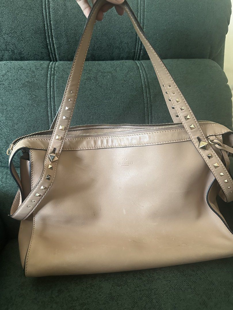 Valentino Garavani Rockstud Bag (Category: Luxury Bags & Wallets) located in Mandaluyong City. Submitted by hdvvv (Listing ID 1429342120, Image 3). Description: Authentic Valentino Garavani Rockstud shoulder tote. • Smooth beige/nude leather • Signature pyramid Rockstuds along the straps • Minimal logo Valentino Garavani” stamped at the front • Structured rectangular body with zip top Visible creases and light scratches - see photos. Complete stu