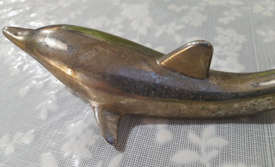 1970's Dolphin Bottle Opener: Nautical Barware (Category: Vintage Collectibles) located in Manila. Submitted by miamiga (Listing ID 1424622325, Image 2). Description: - Vintage dolphin-shaped bottle opener - Silver-colored finish - Includes a bottle opener at the tail - Underside is used for twist off caps - Detailed dolphin design -No longer in mint condition -With signs of age, usage, and stains Size: 6.5".