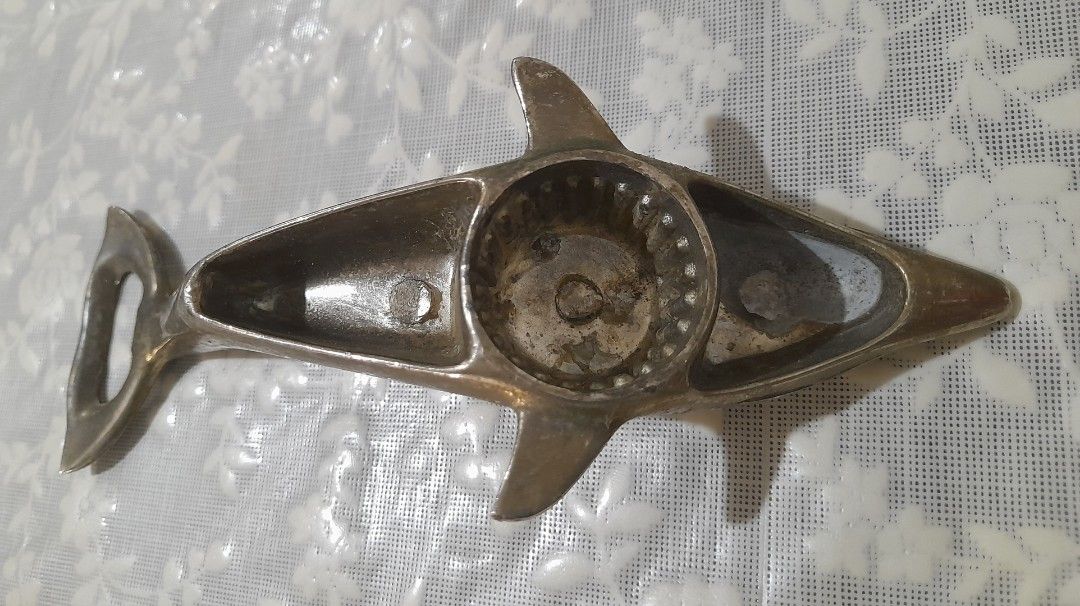 1970's Dolphin Bottle Opener: Nautical Barware (Category: Vintage Collectibles) located in Manila. Submitted by miamiga (Listing ID 1424622325, Image 3). Description: - Vintage dolphin-shaped bottle opener - Silver-colored finish - Includes a bottle opener at the tail - Underside is used for twist off caps - Detailed dolphin design -No longer in mint condition -With signs of age, usage, and stains Size: 6.5".