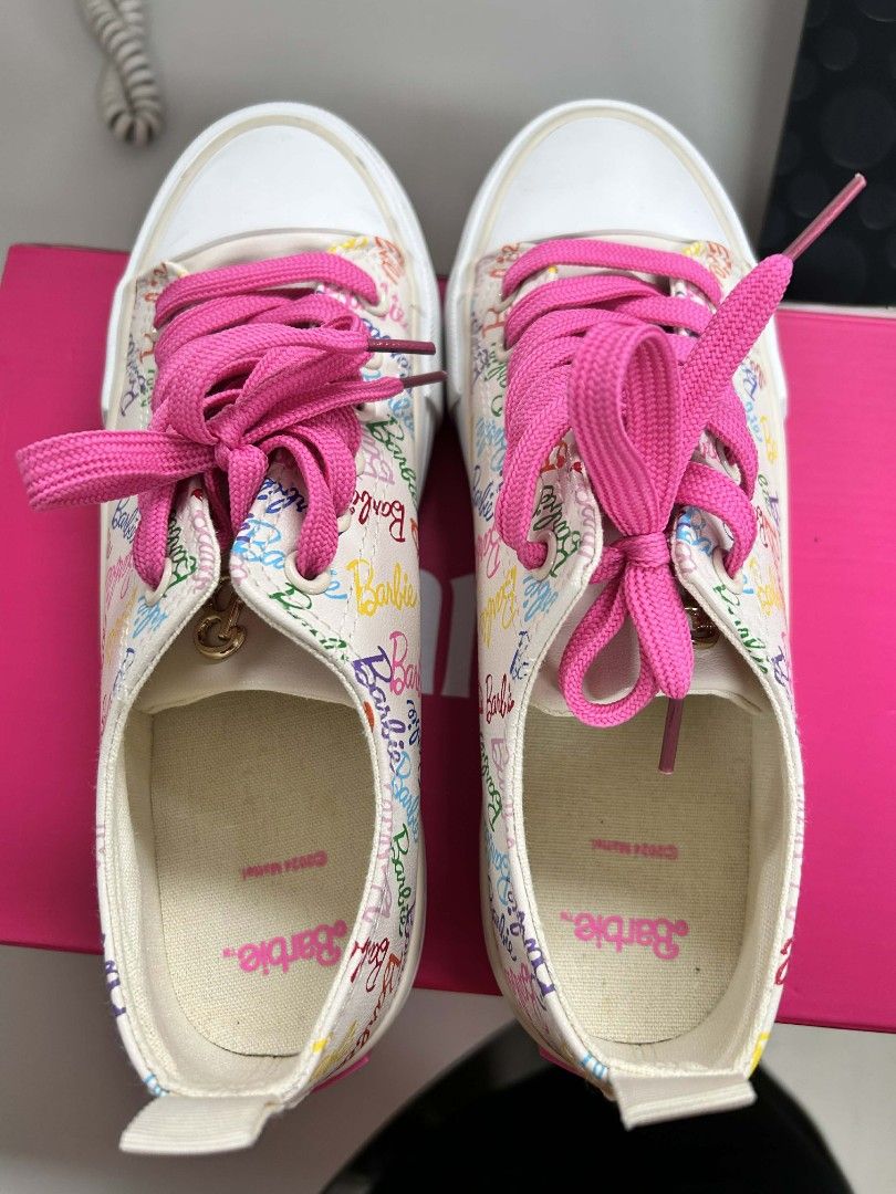 Barbie Sneakers with Pink Laces (Category: Sneakers) located in San Juan City. Submitted by jether03 (Listing ID 1424657020, Image 2). Description: These Barbie sneakers feature a colorful Barbie print on a white background. They have bright pink laces and a white sole. The shoes come with a pink box. The interior of the shoes is printed with the Barbie logo..