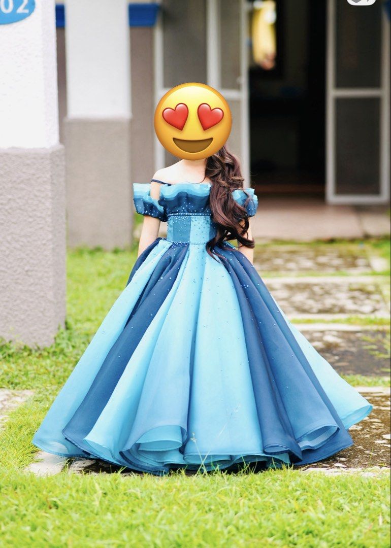 Blue Ball Gown Dress (Category: Babies & Kids Fashion) located in Angeles City. Submitted by mummof3 (Listing ID 1424607085, Image 1). Description: - Elegant blue ball gown - Layered skirt with varying blue shades - Off-shoulder design with darker blue trim - Embellished with subtle details - Ideal for special occasions.