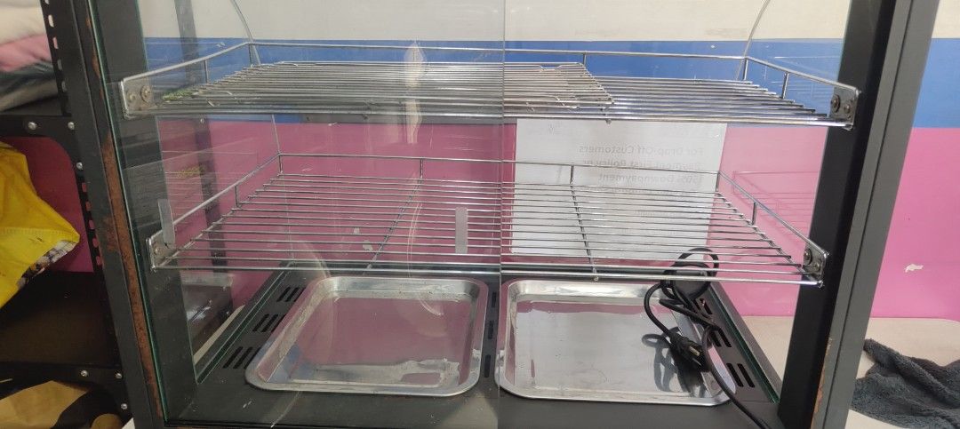 Commercial Food Warmer Display (Category: Food Organization & Storage) located in San Juan City. Submitted by master_aga.criket (Listing ID 1424570648, Image 3). Description: - Commercial food warmer - Multiple shelves and trays - Glass display case with black frame - Temperature control knob - Keeps food warm and ready to serve - Includes power cord - Ideal for restaurants and cafes.