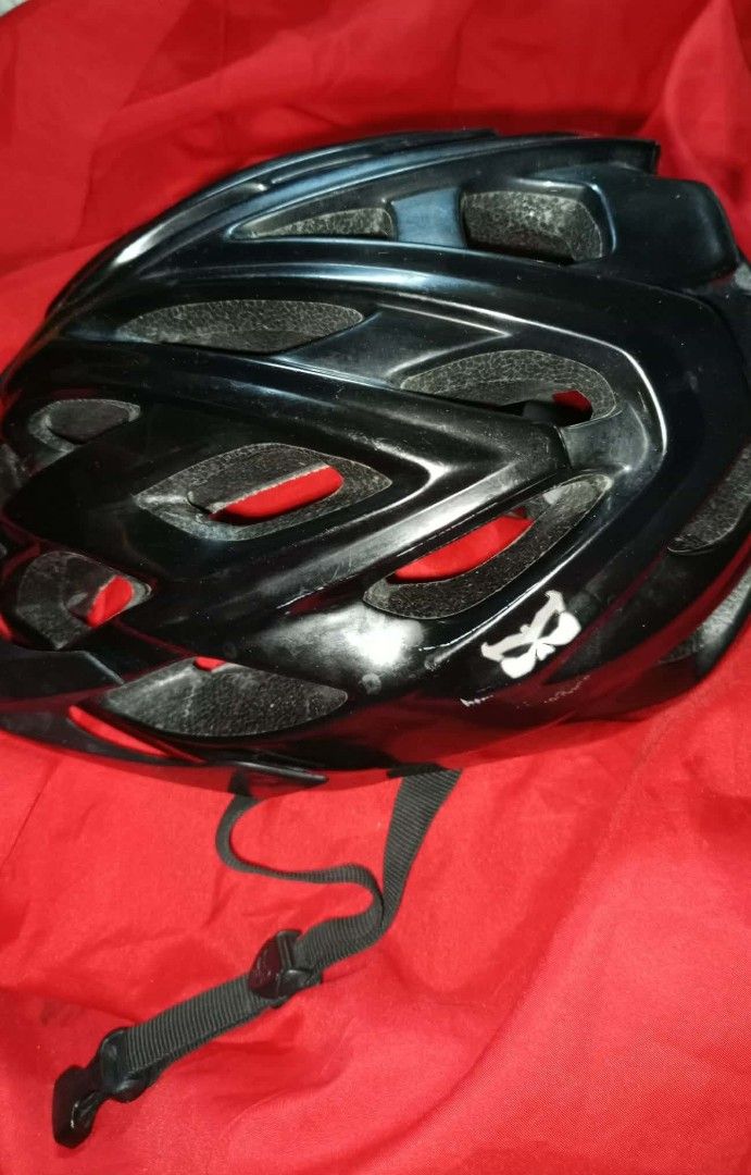 Kali Black Cycling Helmet (Category: Bicycles) located in Kawit. Submitted by monshop714 (Listing ID 1424527001, Image 3). Description: Black cycling helmet, Features the Kali logo on the side. Includes adjustable straps and interior padding for comfort and safety. The helmet has a butterfly logo on the back. The interior has a red lining. USA made.