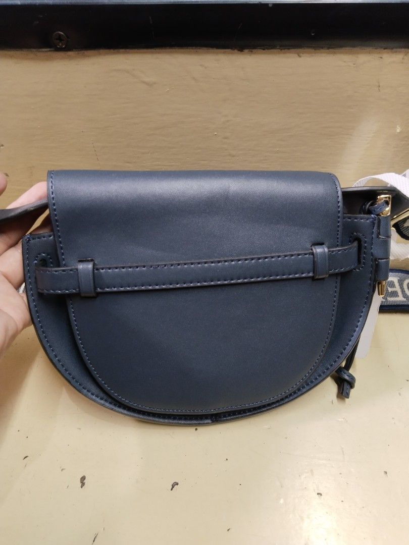 Loewe Gate Dual Mini Bag (Category: Luxury Bags & Wallets) located in Baguio. Submitted by bangtowanv91137 (Listing ID 1424604042, Image 2). Description: Loewe Gate Dual Mini Bag features a navy blue leather exterior with a matching strap. The bag has a saddle shape with the Loewe logo embossed on the front. The interior is lined with a tan suede-like material and includes a small pocket. The strap is a woven design with the Loewe logo..