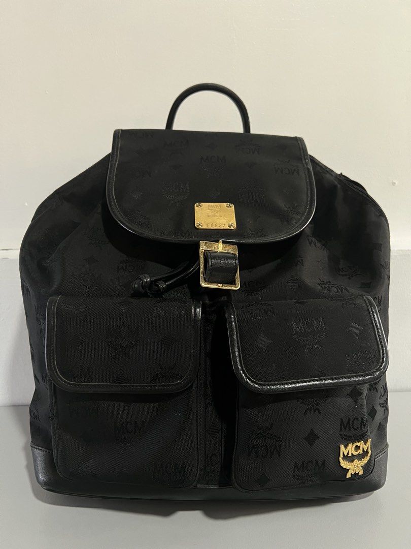 MCM Germany Black Backpack (Category: Luxury Bags & Wallets) located in Batangas. Submitted by aizenaudrix232429 (Listing ID 1424547849, Image 1). Description: - Authentic MCM backpack - Black with signature logo pattern - Flap closure with buckle - Two front pockets - Top handle - Side zipper - Adjustable straps - Gold-tone logo emblem.