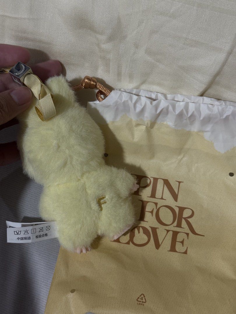 Pop Mart Labubu Pin For Love (Category: Character Goods) located in Valenzuela. Submitted by danabananani (Listing ID 1424627850, Image 2). Description: - Pop Mart Pin For Love Keychain - Features a fluffy yellow character - Smiling face design - Includes a matching drawstring bag - Silver ring keychain - Ribbon with the letter "F" - Character has "F" embroidery on the back - Includes a tag - RFS: Not prio color/letter.