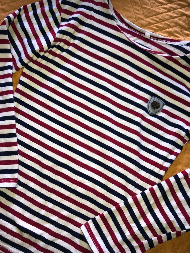 Striped Long Sleeve Shirt (Category: Longsleeves) located in Alcala. Submitted by grisch (Listing ID 1424527511, Image 3). Description: - Striped long sleeve shirt - Brand: Jeans - Size: XS-S - Color: Red, navy, and white stripes - Features a small emblem detail - Versatile and stylish has a super minor issue (check last image).