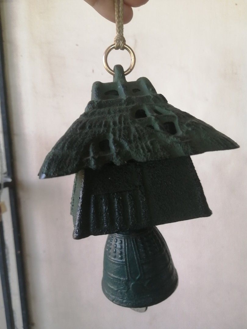 Vintage Japanese Cast Iron Wind Chime (Category: Other Home Decor) located in Liloan. Submitted by aidolcapz88 (Listing ID 1424604146, Image 1). Description: Vintage wind chime features a unique Japanese design. It has a tiered structure with a bell at the bottom. The chime is suspended by a rope and a metal ring. The color is a dark green..