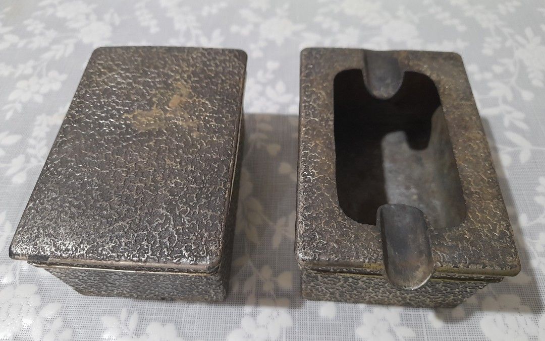 Vintage Metal Ashtray and Cigarette Case Set (Category: Vintage Collectibles) located in Manila. Submitted by miamiga (Listing ID 1424618210, Image 1). Description: - Features a unique textured design - Includes both an ashtray and a cigarette case. - Aged appearance with signs of usage, showing signs of vintage charm. - The cigarette case has a gold interior to prevent the metal from reacting with the cigarette. - Perfect for collectors or those