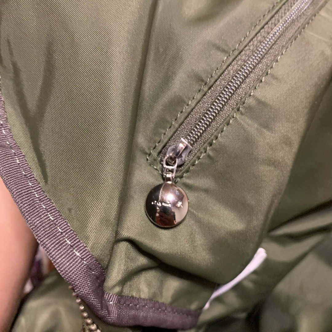 Agnes B. Voyage Green Shoulder Bag (Category: Luxury Bags & Wallets) located in Carmen. Submitted by ar_thrift00 (Listing ID 1424798345, Image 2). Description: Authentic Agnes B. Voyage shoulder bag in green. Features a top handle and a detachable shoulder strap. It has a front zipper pocket and a main compartment with a zipper closure. The interior has a small pocket with a brand tag. The bag has silver-tone hardware and a nylon exterior..