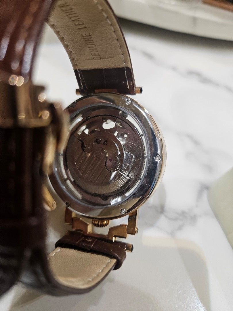Difful Original Automatic Skeleton Watch (Category: Watches) located in Kuala Lumpur. Submitted by freewhale-6bcf (Listing ID 1424866061, Image 2). Description: Difful Original Automatic watch features a skeleton design, showcasing the intricate inner workings. It has a brown leather strap and a gold-colored case. The watch also has a moon phase indicator. The back of the watch is transparent, revealing the automatic movement. The clasp is brande