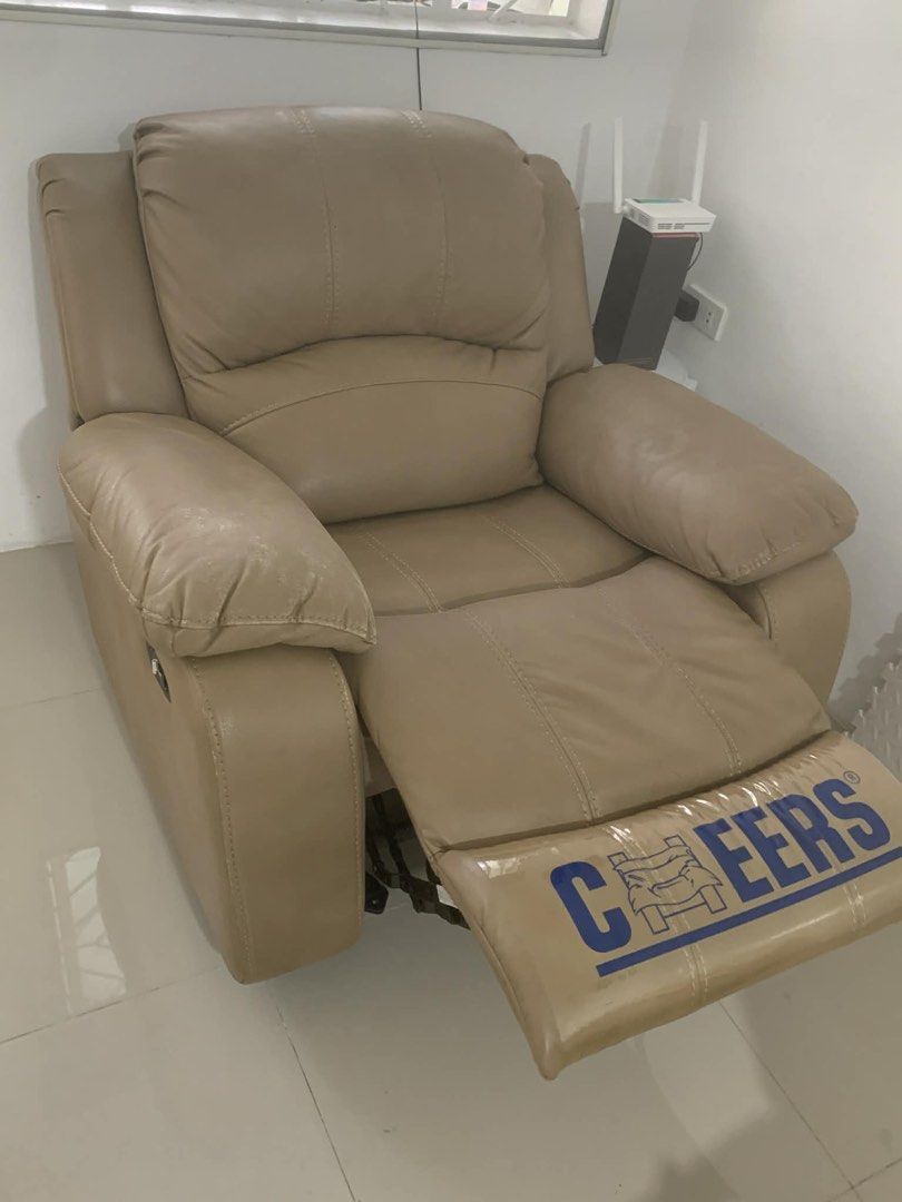 La Sedia Recliner Chair (Category: Chairs) located in Quezon City. Submitted by My_Santos (Listing ID 1424766526, Image 2). Description: Comfortable recliner chair with a beige leather finish. Features a reclining mechanism for added relaxation. The chair has a Cheers logo on the footrest. Includes a white cover for protection. Perfect for living rooms or entertainment areas. RFS: Declutter; comes with free cover Buyer to shoulder lalamove sf aro