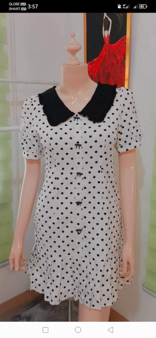 Polka Dot Dress with Black Collar (Category: Dresses) located in Legazpi City. Submitted by riris.unique.finds (Listing ID 1424823528, Image 1). Description: Dress features a classic polka dot pattern with a contrasting black collar. It has short sleeves and a button-down front. The dress has a fitted bodice and a flared skirt with a ruffled hemline. It is a stylish and versatile piece suitable for various occasions..