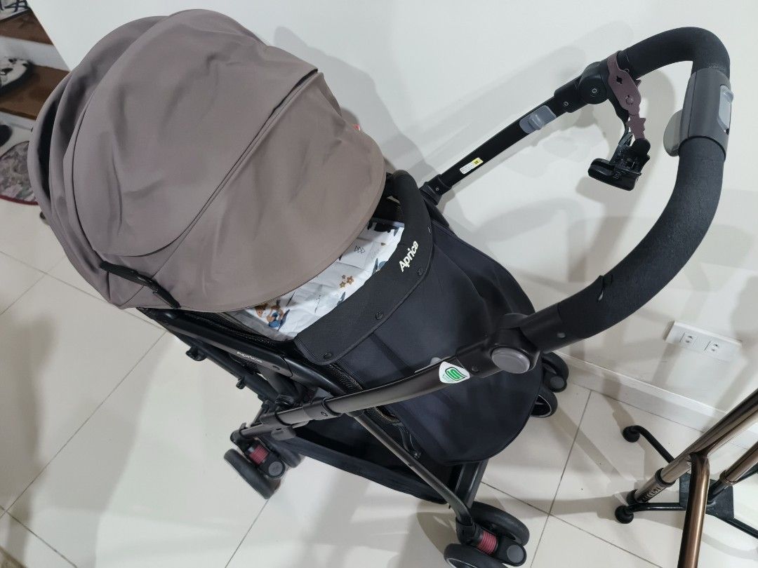 Aprica Stroller (Category: Strollers) located in Manila. Submitted by shopclothes.ph (Listing ID 1424884713, Image 3). Description: Aprica stroller with a brown canopy and black frame. Features a padded seat and a front bar. The stroller has four wheels and a compact design..