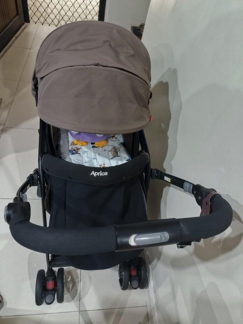 Aprica Stroller (Category: Strollers) located in Manila. Submitted by shopclothes.ph (Listing ID 1424884713, Image 2). Description: Aprica stroller with a brown canopy and black frame. Features a padded seat and a front bar. The stroller has four wheels and a compact design..