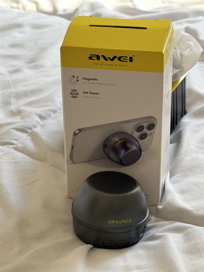 Awei KA53 Magnetic Mini Wireless Speaker (Category: Soundbars, Speakers & Amplifiers) located in Paranaque City. Submitted by karloagoda (Listing ID 1424939619, Image 3). Description: Awei KA53 magnetic mini wireless speaker. Features 4h music play and 5W output power. Includes the speaker, charging cable, and user manual. The speaker is dark grey with three control buttons. The box shows the speaker attached to a phone. It has a magnetic feature