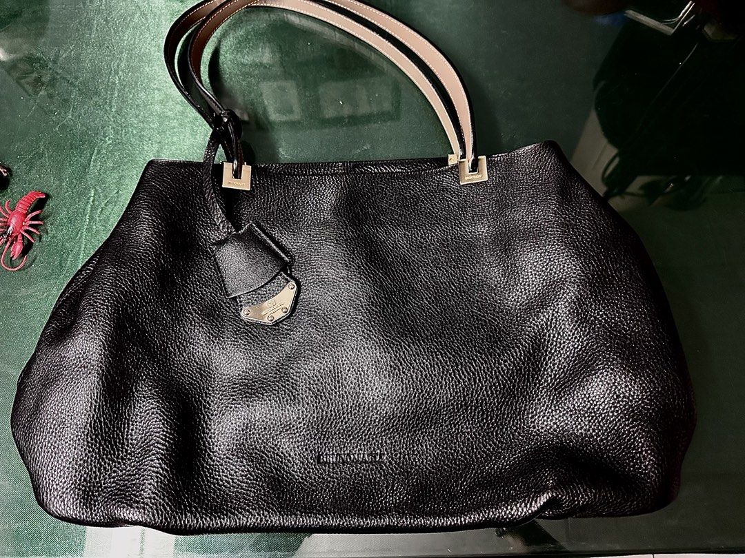 Bruno Magli Black Leather Tote Bag (Category: Luxury Bags & Wallets) located in Angeles City. Submitted by ritenianstuff (Listing ID 1424973727, Image 1). Description: Genuine leatherblack tote bag by Brunomagli. Features a spacious interior with multiple compartments and a zip closure. Includes a detachable leather tag with the brand's logo. The bag has double handles with a unique design. The interior lining has a branded pattern. Gold hardware