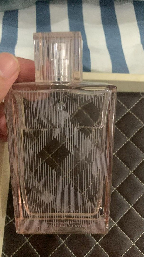 Burberry Brit Sheer Eau de Toilette (Category: Fragrance & Deodorants) located in Valenzuela. Submitted by flzoneeee (Listing ID 1424906614, Image 1). Description: Bottle of Burberry Brit Sheer Eau de Toilette. The perfume bottle has a pink hue and a clear cap. The bottle features a distinctive pattern. The perfume is in a rectangular bottle with a clear cap. The bottle is held by a hand..