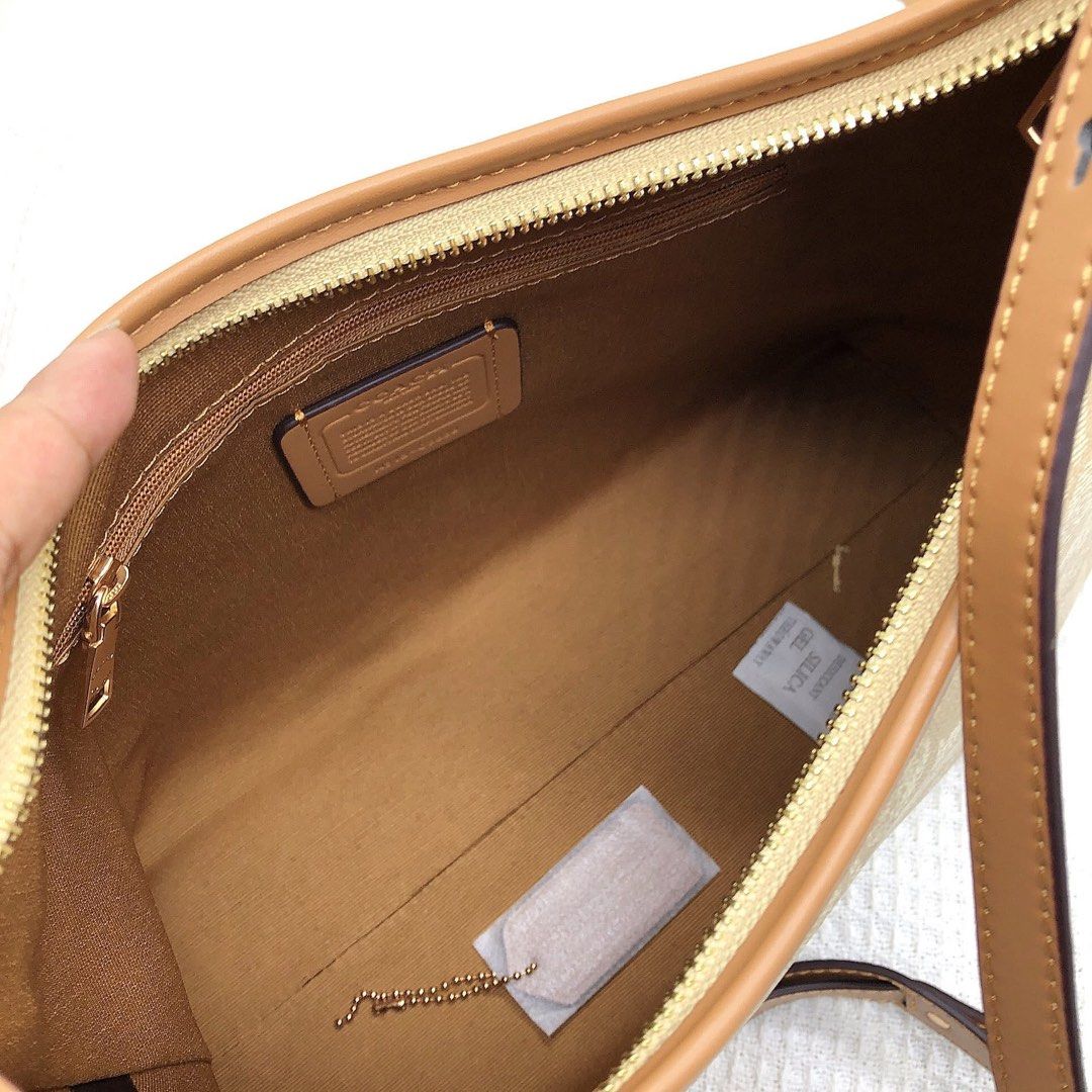 Coach Signature Shoulder Bag (Category: Luxury Bags & Wallets) located in Manila. Submitted by clairetot (Listing ID 1424912751, Image 3). Description: Coach shoulder bag with signature pattern. Features a zip closure and an interior pocket. Includes a detachable strap. The bag has a brown leather trim and a Coach tag inside. Comes with a Coach paper bag..