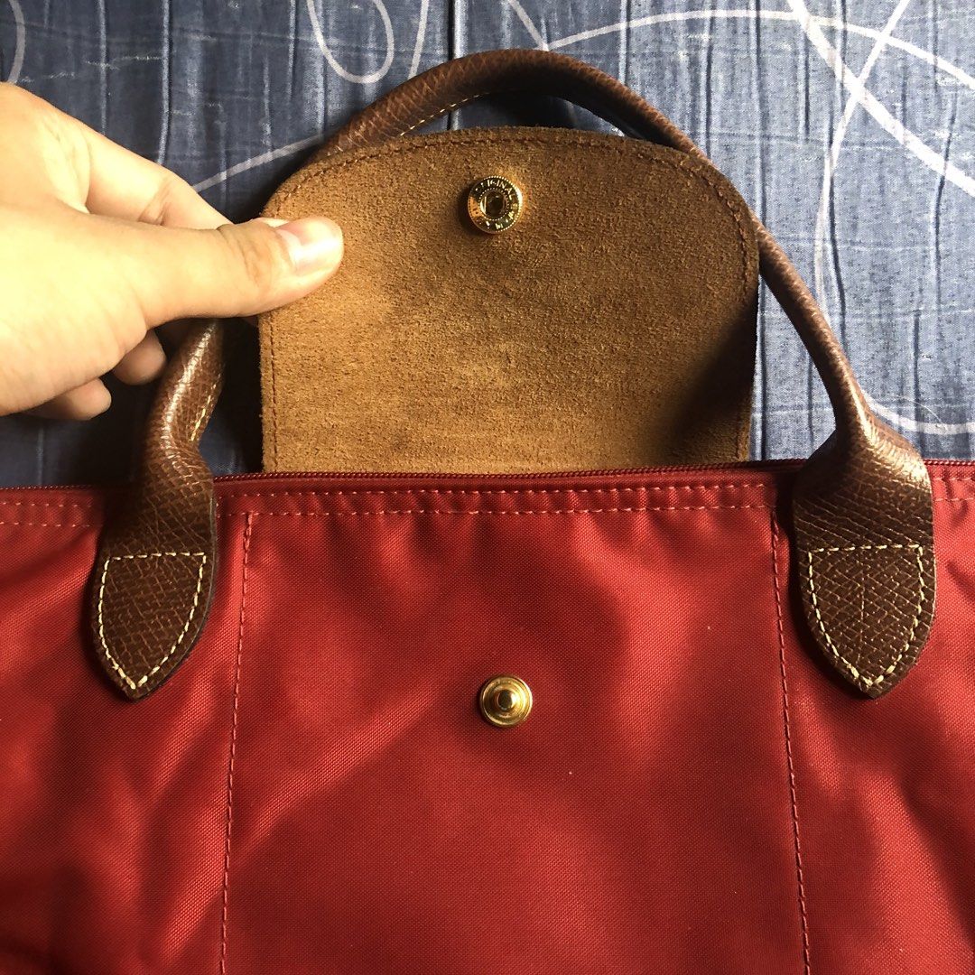Longchamp Le Pliage M depose Handbag (Category: Luxury Bags & Wallets) located in Mandaluyong City. Submitted by bestofluxielux (Listing ID 1424962566, Image 3). Description: - Authentic Longchamp Le Pliage handbag -Medium size - Red nylon exterior - Brown leather accents - Zipper closure with Longchamp logo charm - Beige lining - Interior pocket - Snap closure - Longchamp logo on front -With staining inside - Made in China.