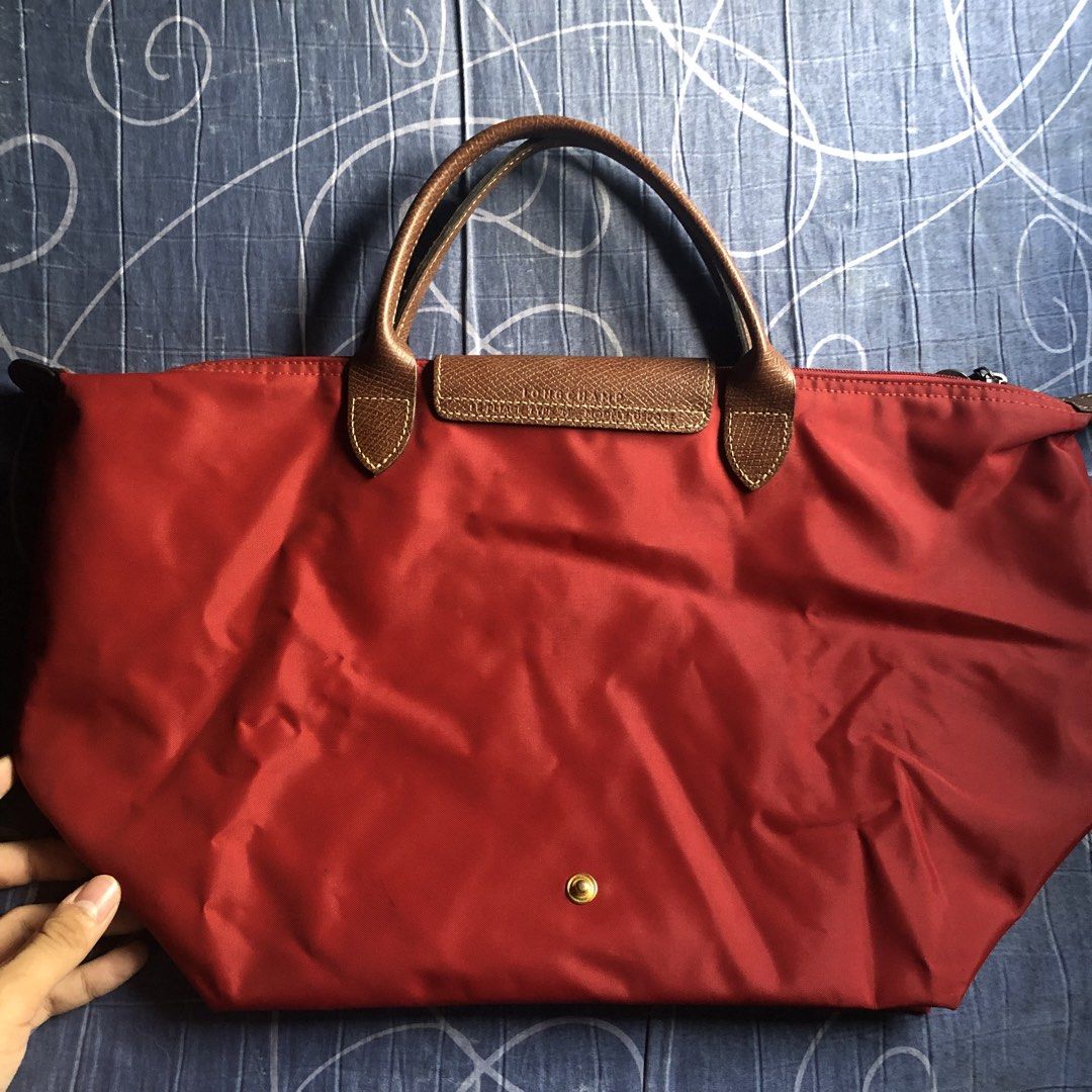 Longchamp Le Pliage M depose Handbag (Category: Luxury Bags & Wallets) located in Mandaluyong City. Submitted by bestofluxielux (Listing ID 1424962566, Image 2). Description: - Authentic Longchamp Le Pliage handbag -Medium size - Red nylon exterior - Brown leather accents - Zipper closure with Longchamp logo charm - Beige lining - Interior pocket - Snap closure - Longchamp logo on front -With staining inside - Made in China.