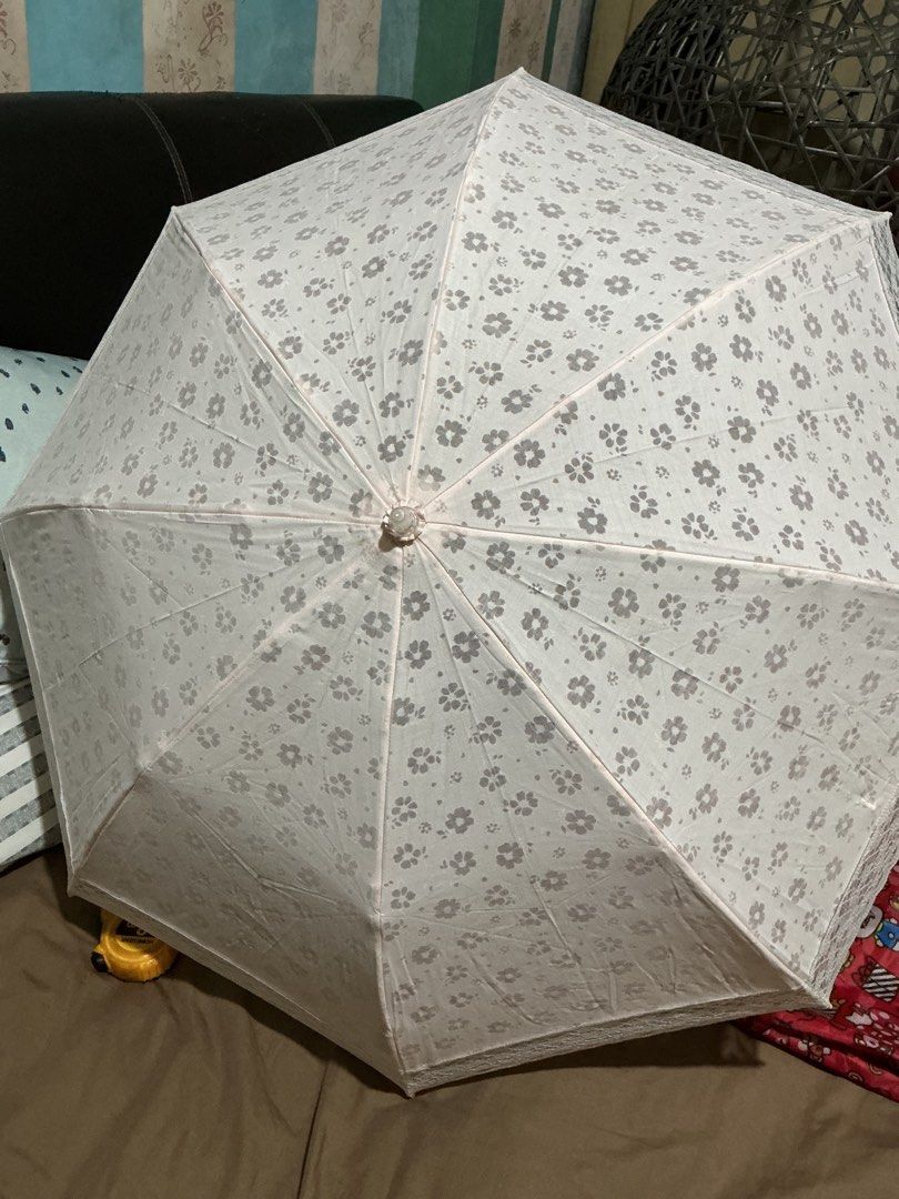 Metrocity Floral Lace Umbrella (Category: Umbrellas) located in Angeles City. Submitted by goodbuysathome (Listing ID 1425023027, Image 1). Description: Elegant Metrocity umbrella featuring a delicate floral pattern and lace trim. The umbrella is light pink with a clear handle and gold accents. It has a strap with the Metrocity logo. When open, the umbrella measures approximately 45cm in length. When closed, it measures approximately 25cm in leng