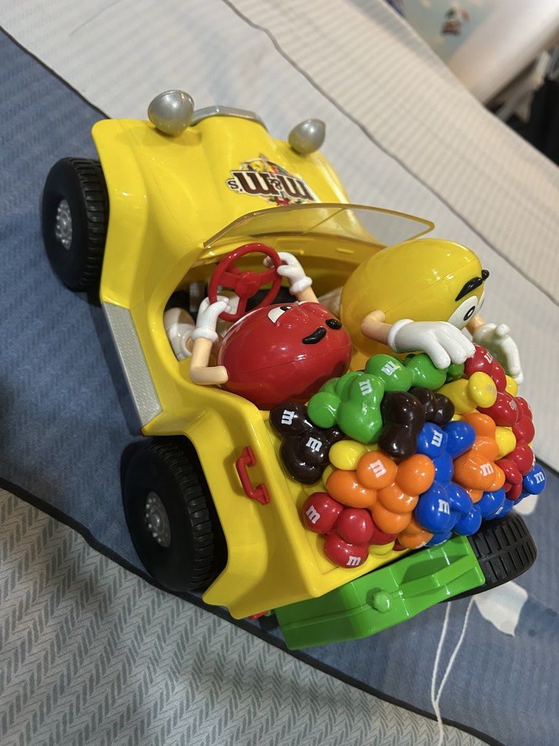 M&M's Candy Dispenser Car (Category: Vehicle & Diecast Models) located in Manila. Submitted by alainachu (Listing ID 1425037071, Image 3). Description: Fun M&M's candy dispenser shaped like a yellow car. It features the M&M's characters, with the red M&M driving and the yellow M&M waving. The car is filled with colorful M&M's candies. It has a clear windshield and headlights. The back of the car has a green compartment. Loc: San Juan City.