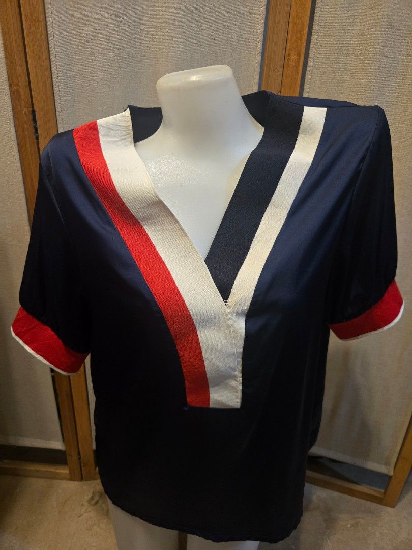 Navy Blue Striped Polo Shirt (Category: Blouses) located in Pasig City. Submitted by leildyne (Listing ID 1424979641, Image 2). Description: Navy blue polo shirt with white and red stripes on the collar and sleeves. Features a white panel on the chest with red and white stripes. The sleeves have red cuffs. There is a small imperfection on the white panel..