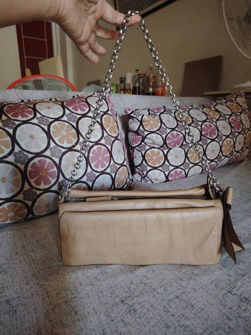 Nina Ricci Beige Chain Bag (Category: Luxury Bags & Wallets) located in Muntinlupa City. Submitted by jovyrivera0824 (Listing ID 1424904959, Image 1). Description: Beige handbag with a chain strap. Features a zipper closure and multiple compartments. Includes a detachable charm with the Nina Ricci logo. The bag has a flap closure with a button. The interior lining is a lighter beige color.No stain inside. Genuine leather. Original Nina Ricci. Sil