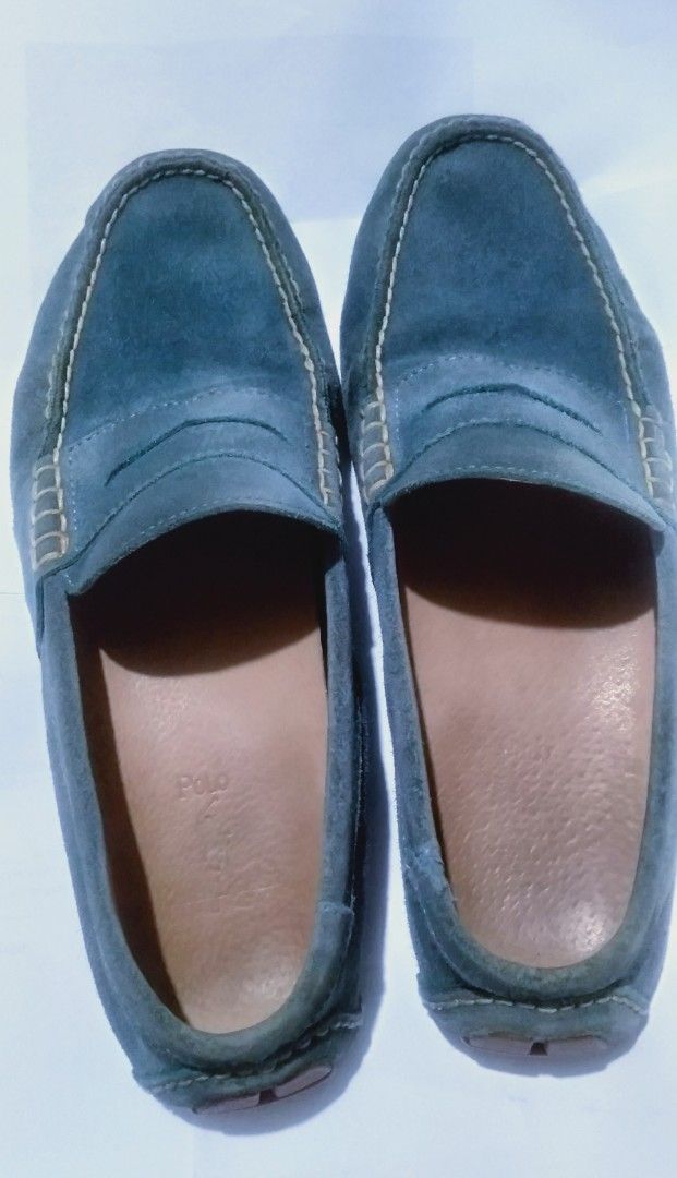 Polo Ralph Lauren Suede Loafers (Category: Dress Shoes) located in Naga. Submitted by pec3c (Listing ID 1425017882, Image 2). Description: These Polo Ralph Lauren loafers feature a suede upper in a blue-grey color. They have a classic penny loafer design with a stitched detail around the top. The insole is a light brown leather, and the Polo logo is visible. The soles show some wear..