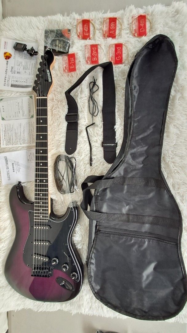 Selder Electric Guitar with Accessories (Category: Musical Instruments) located in Balagtas. Submitted by misteramarijapansurplus (Listing ID 1425049491, Image 1). Description: Selder electric guitar comes with a soft case, strap, cable, and a set of new strings. It includes a tuner and some paperwork. The guitar has a black and purple finish. The guitar has a black headstock and a rosewood fretboard. GUITAR with BAG ONLY 4500 loc Panginay Balagt