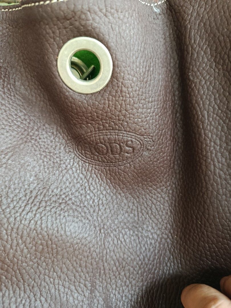 Tod's Brown Leather Handbag (Category: Luxury Bags & Wallets) located in Cavite. Submitted by yapelrich21 (Listing ID 1424899765, Image 2). Description: Brown leather handbag from Tod's. Features a large, open design with a single handle. The bag has a distinctive metal eyelet detail with a green interior. The Tod's logo is embossed on the front. The stitching is white..