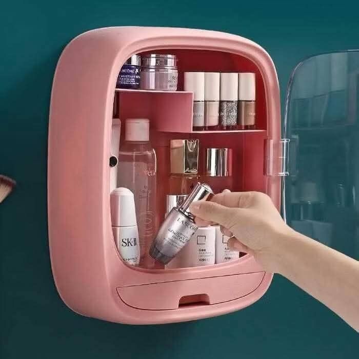 Wall-Mounted Cosmetic Organizer (Category: Makeup) located in Quezon City. Submitted by anghies_shop (Listing ID 1425055184, Image 2). Description: Pink wall-mounted cosmetic organizer features multiple compartments and a drawer for storing beauty products. It has a clear door for easy visibility and a compact design. The organizer's dimensions are approximately 20cm in height, 15.5cm in width, and 11cm in depth. It includes shelves and a drawer 