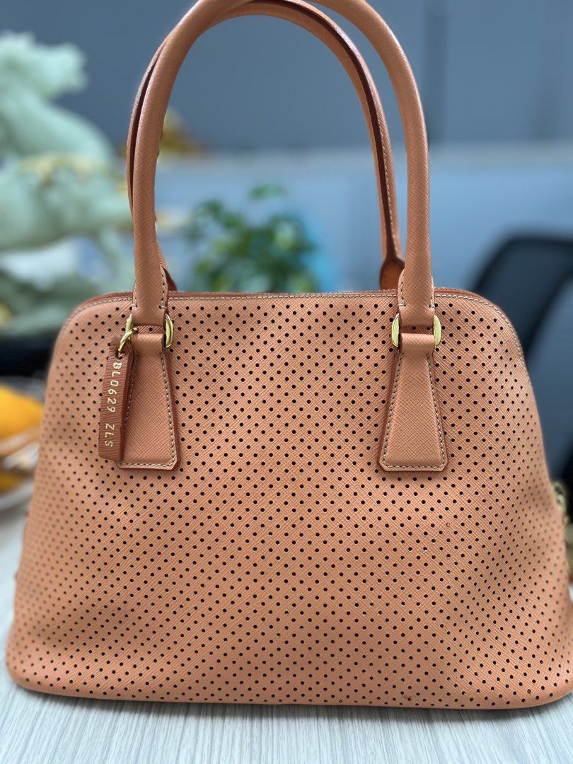 Authentic Limited Edition Prada Perforated Leather Dome Handbag (Category: Luxury Bags & Wallets) located in Cagayan de Oro. Submitted by riggstuffs (Listing ID 1425116231, Image 2). Description: ➡️ Guaranteed Authentic Limited Edition Prada handbag features a perforated leather design. ➡️ Made in Italy ➡️ With code ➡️ Dome shape with dual top handles and a zip closure with a detachable leather tag and gold-tone hardware. ➡️ The bag has a peach c