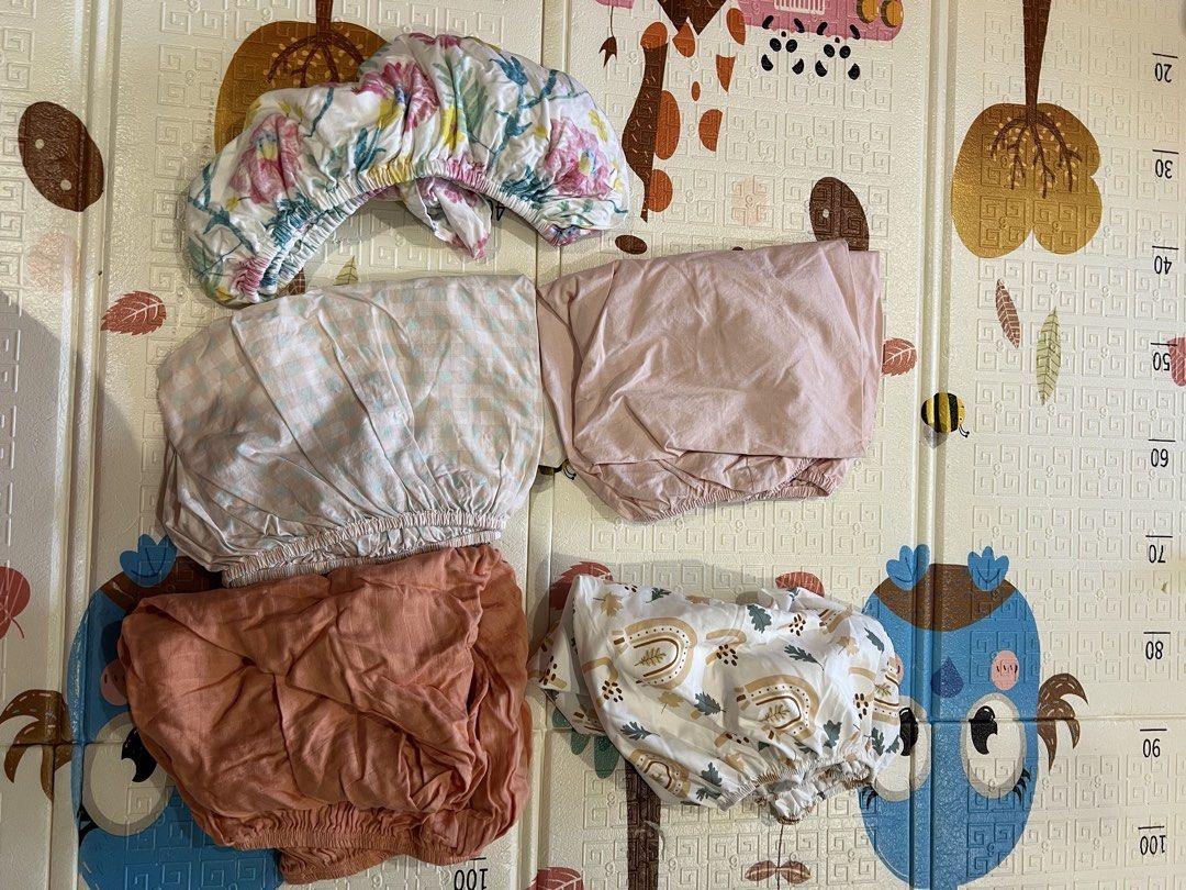 Bundle Fitted Crib Sheets Set (Category: Bedding & Towels) located in Manila. Submitted by declutterforamari (Listing ID 1425056967, Image 1). Description: Set of fitted crib sheets in various colors and patterns. Includes floral, gingham, solid pink, rust, and rainbow/leaf designs. All sheets have elastic edges and can fit any mattress in a crib. .