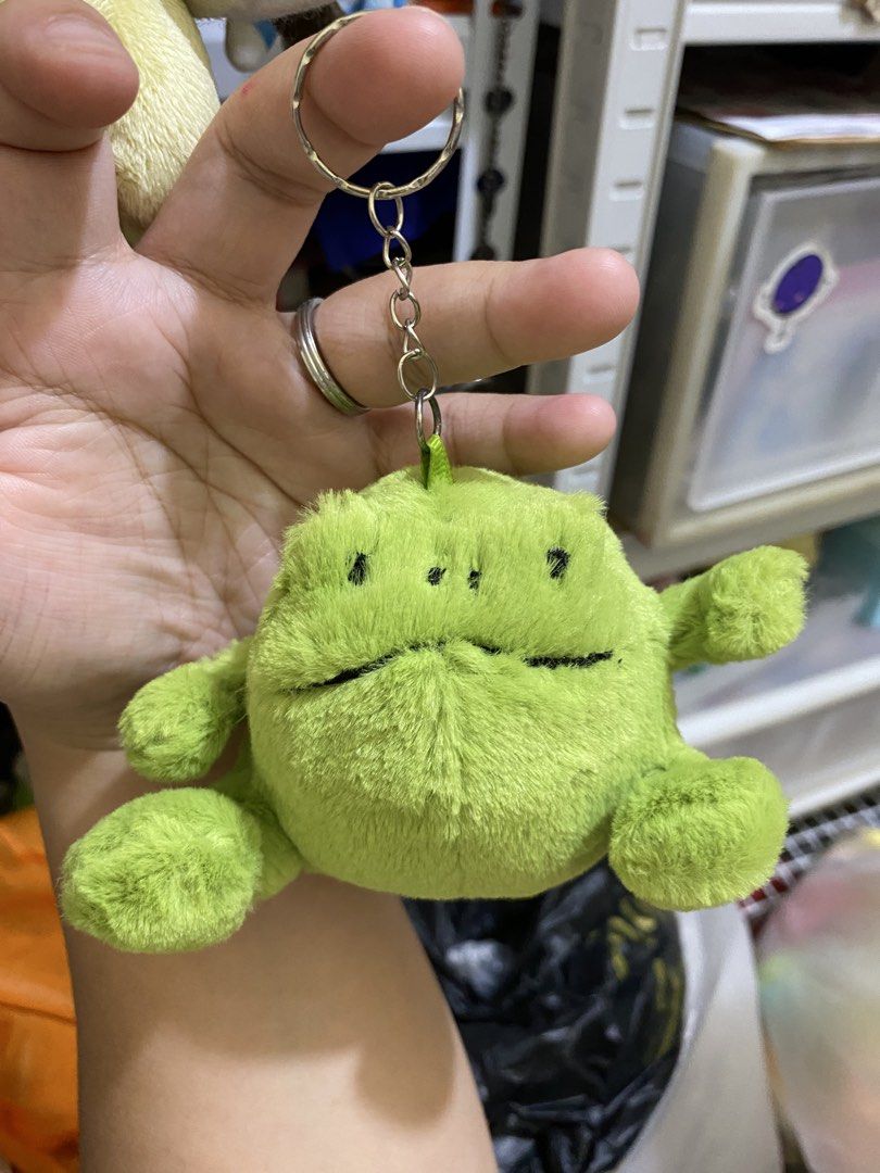 Jellycat Green Frog Keychain (Category: Plushies & Soft Toys) located in Imus. Submitted by mnmv23 (Listing ID 1425244083, Image 2). Description: Adorable Jellycat green frog plushie keychain. Features a soft, plush texture and a cute, smiling face. Includes a metal keychain ring for easy attachment to bags or keys. The tag indicates it's a Jellycat London product. A perfect gift for plushie collectors or anyone who loves cute accessories. Sold a