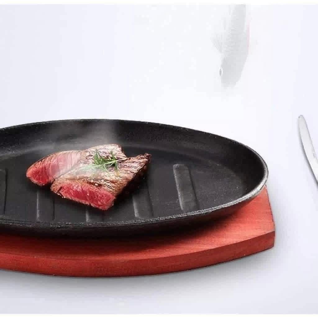 Oval Sizzling Plate with Wooden Base (Category: Cookware & Accessories) located in Manila. Submitted by yzcartph (Listing ID 1425075243, Image 3). Description: Sizzling plate is perfect for serving various dishes like steak, fried eggs, and fried rice. It comes with a wooden base for easy handling and serving. The plate is oval-shaped with a black finish and features grill lines. It's ideal for both home cooking and restaurant use. The plate is s