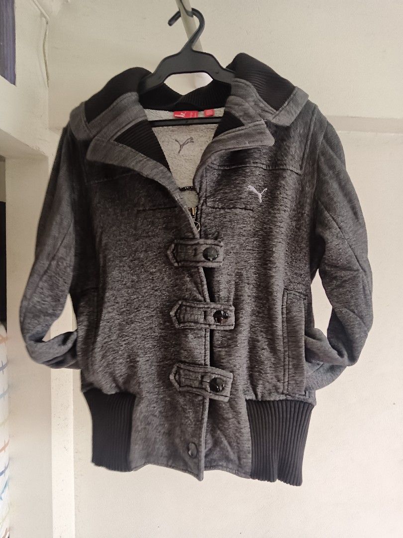 AS IS: Puma Vintage Gray Jacket with Hood (Category: Coats, Jackets and Outerwear) located in San Juan City. Submitted by frugala (Listing ID 1425090311, Image 2). Description: *Puma Button Zip-Up Y2K Charcoal 2008s* Gray Puma jacket with a hood. Features a zipper closure and button details. Ribbed/ woven pattern. The jacket has a ribbed hem and cuffs w/ visible signs of wear. The Puma logo is visible on the chest. With small tear (not a hole) on