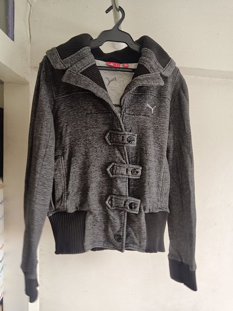 AS IS: Puma Vintage Gray Jacket with Hood (Category: Coats, Jackets and Outerwear) located in San Juan City. Submitted by frugala (Listing ID 1425090311, Image 1). Description: *Puma Button Zip-Up Y2K Charcoal 2008s* Gray Puma jacket with a hood. Features a zipper closure and button details. Ribbed/ woven pattern. The jacket has a ribbed hem and cuffs w/ visible signs of wear. The Puma logo is visible on the chest. With small tear (not a hole) on