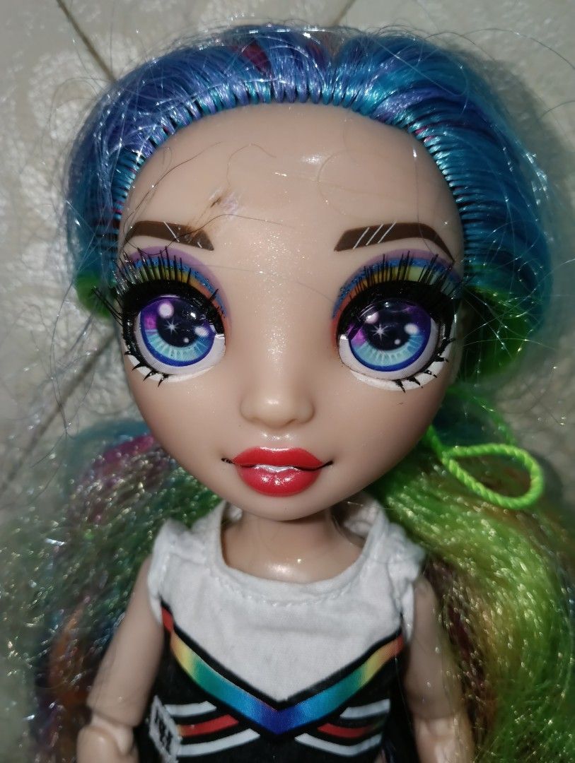 Rainbow High Cheer Doll (Category: Kids Toys) located in Angono. Submitted by lala_tan (Listing ID 1425243405, Image 2). Description: Rainbow High Cheer doll with vibrant rainbow hair and detailed makeup. She is wearing a white and black crop top, black shorts with rainbow stripes, and black sandals. The doll has articulated limbs and is ready for play or display. have flaws sa fez.