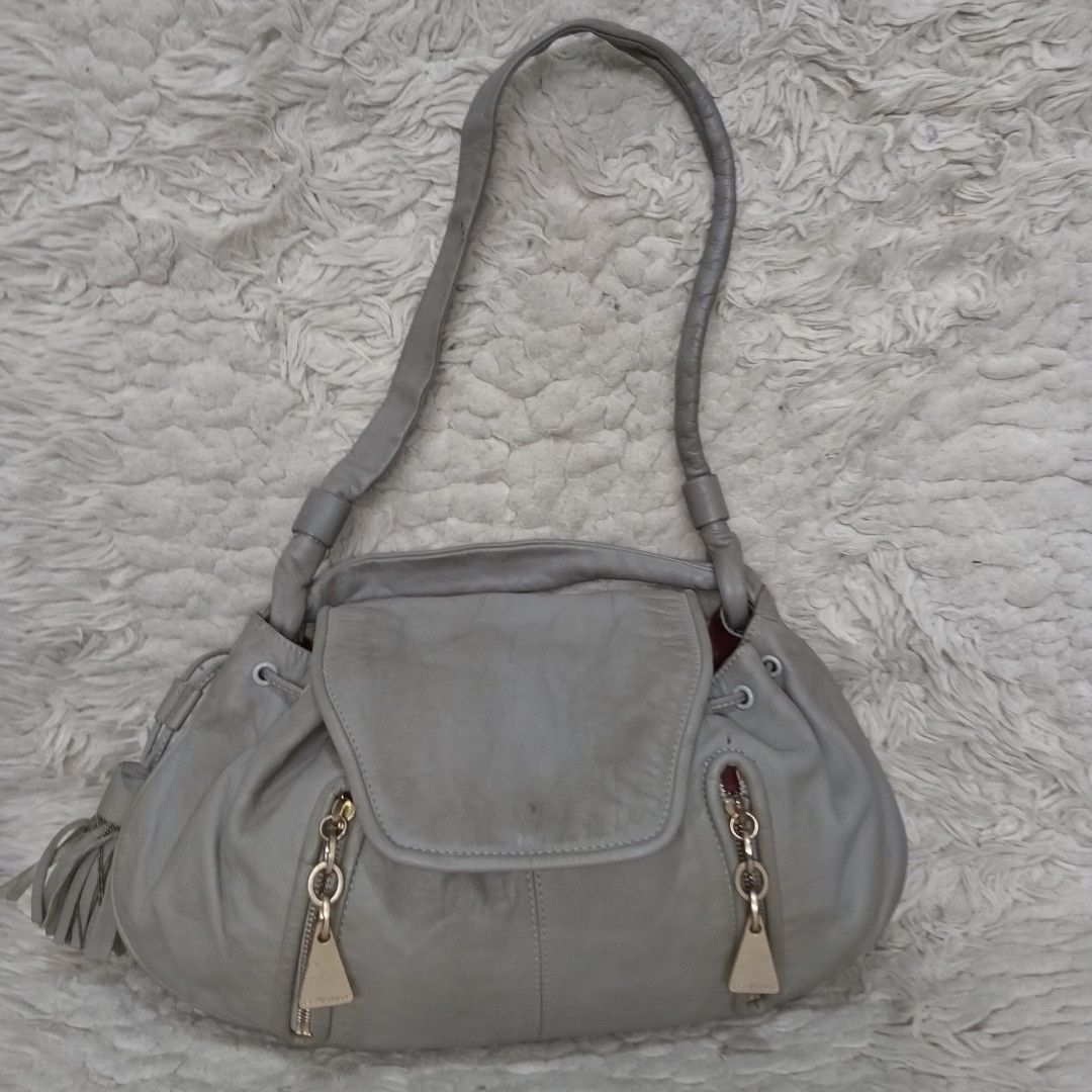 See by Chloe Grey Leather Handbag (Category: Luxury Bags & Wallets) located in Baguio. Submitted by sheren_signatures (Listing ID 1425170475, Image 1). Description: See by Chloe handbag features a soft grey leather exterior with gold-toned hardware. It has a flap closure and two zippered pockets on the front. The interior is lined with a pink fabric and includes a small pocket. The bag has a shoulder strap and a tassel detail. Made in Morocco..