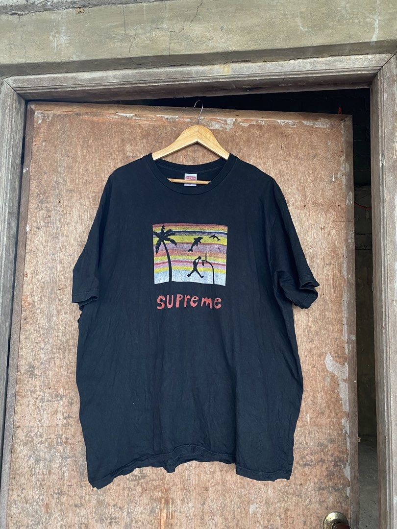 Supreme Basketball Graphic Tee XL (Category: Tshirts & Polo Shirts ) located in Manaoag. Submitted by mangthrifttayo (Listing ID 1425059014, Image 1). Description: Black Supreme t-shirt featuring a basketball graphic on the front. The graphic includes a palm tree, dolphins, and a basketball player. The shirt is size XL and made of 100% cotton. The Supreme logo is visible on the tag..