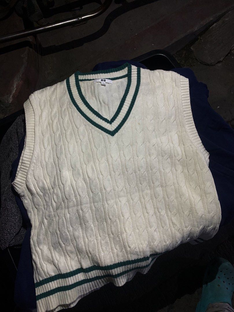 Uniqlo Cable Knit Vest (Category: Vests) located in Manila. Submitted by euphoriathriftco (Listing ID 1425223562, Image 1). Description: Cream-colored cable knit vest from Uniqlo. Features a V-neck design with green trim along the neckline and hem. The vest has a sleeveless design. The tag is visible in the image. Made of a knit material..