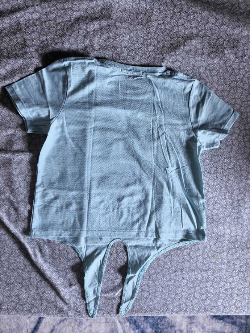 BTS Graphic Tee with Tie Detail (Category: Babies & Kids Fashion) located in Mandaluyong City. Submitted by berriesweet (Listing ID 1425363117, Image 2). Description: Light blue t-shirt featuring a BTS graphic on the front. It has short sleeves and a tie detail at the bottom. The back of the shirt is plain light blue. There is a small stain on the front of the shirt..