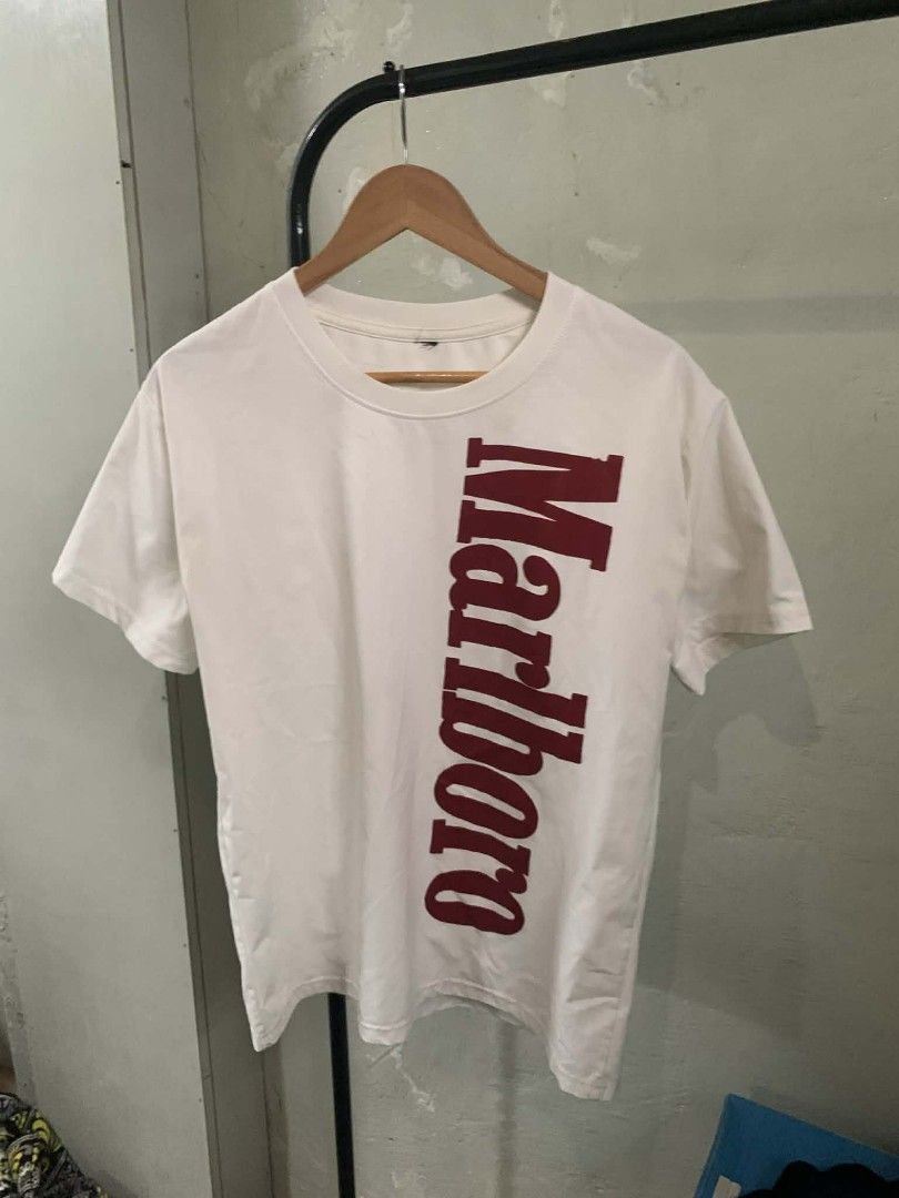 Marlboro White T-shirt (Category: Tshirts & Polo Shirts ) located in Cordova. Submitted by statanthrifts (Listing ID 1425351841, Image 1). Description: White t-shirt featuring the Marlboro logo in red. The logo is printed vertically on the left side of the shirt. The shirt has short sleeves and a crew neck. large.
