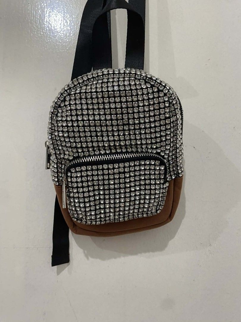 Alexander Wang cruiser embellished Mini Backpack sling (Category: Luxury Bags & Wallets) located in Pasig City. Submitted by psg2019 (Listing ID 1425558174, Image 2). Description: Mini backpack features a dazzling rhinestone exterior with a brown suede-like bottom. It has a front zippered pocket and a top zipper closure. The interior includes a brand tag. The backpack has black straps and silver-toned hardware. It's a stylish accessory for carryi